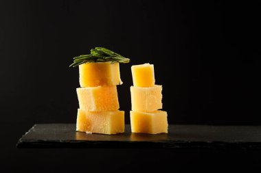 Siyah tahta veya kayrak üzerinde aromatik peynir parçaları