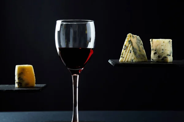 Portie rode wijn en kleine stukjes aromatische blauwe kaas — Stockfoto