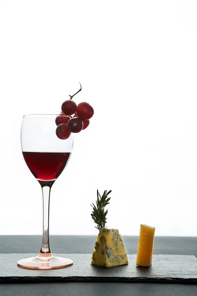 Glas rode wijn gegarneerd met druiven en stukjes hartige kaas — Stockfoto