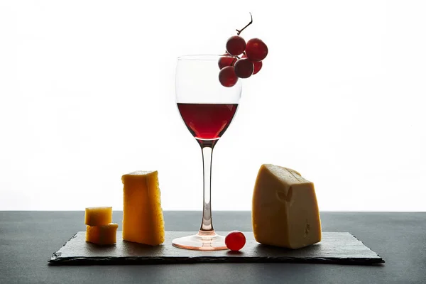 Glas rode wijn gegarneerd met druiven en verschillende soorten kaas — Stockfoto