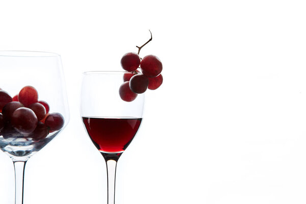 Red grape and wine in crystal glasses on white background