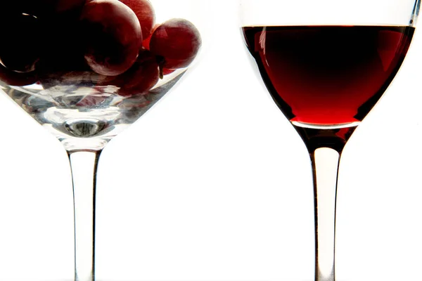 Verres en cristal avec raisin rouge et vin savoureux sur fond blanc — Photo