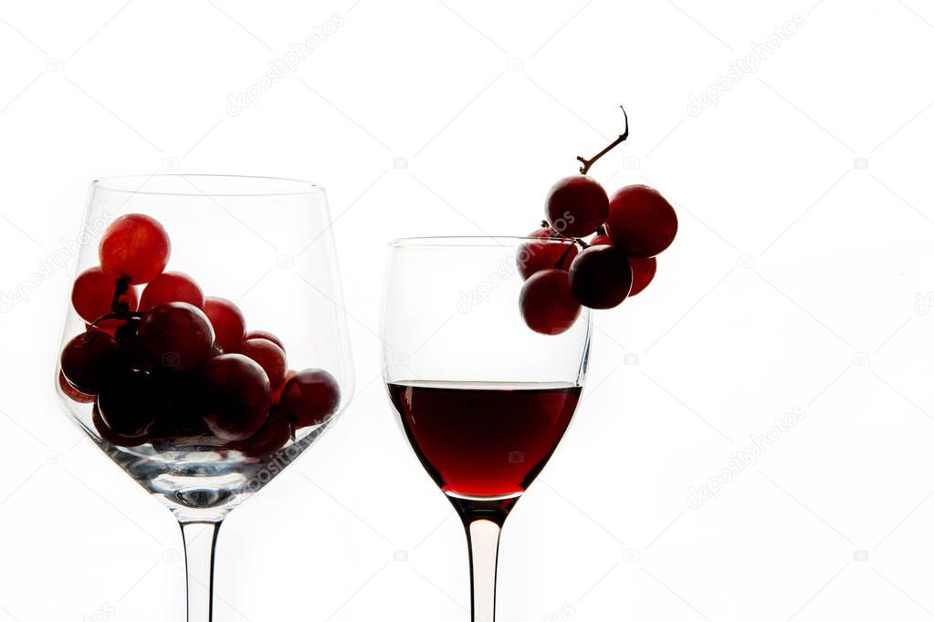 Crystal glasses with red grape and tasty wine on white background