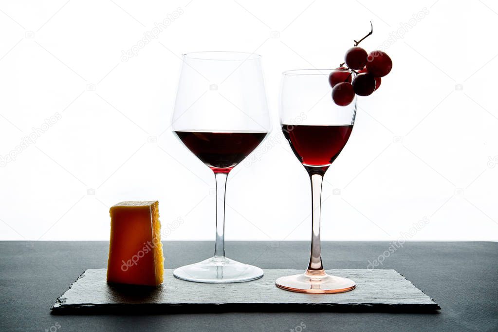 Composition of glasses with ripe grape and red wine served on slate board