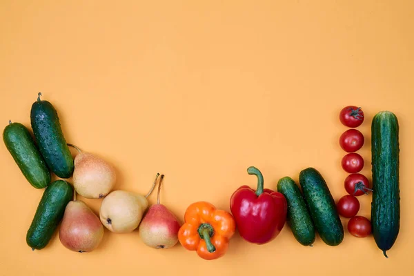 Colorful fruit and vegetables pattern or background. Composition of different ripe vegetables and pears on orange background