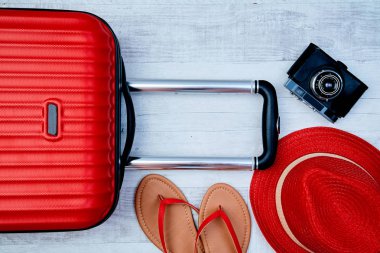 Hafif arka planda flip-flop ve retro kamera yanında kırmızı bavul yukarıdan. Seyahat bloglama veya kadın blogger veya yaz tatili anlayışı.