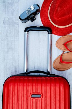 Hafif arka planda flip-flop ve retro kamera yanında kırmızı bavul yukarıdan. Seyahat bloglama veya kadın blogger veya yaz tatili anlayışı.
