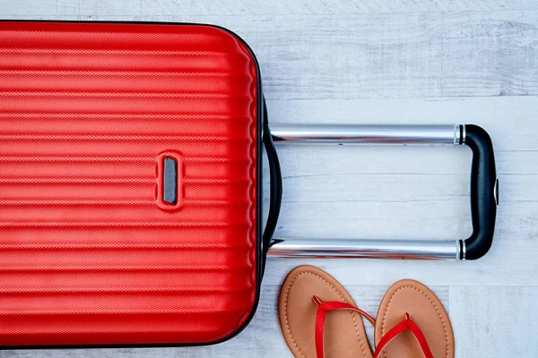 Von oben roter Koffer neben Flip-Flop auf hellem Hintergrund. Reiseblogging oder Bloggerin oder Sommerferienkonzept. — Stockfoto