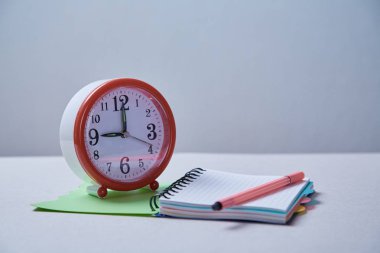 Zaman yönetimi, son tarih ve zamanlama kavramı: mavi arka planda çalar saat ve Notebook.