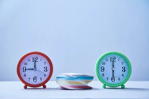 Керування часом та концепція розкладу: стек наклейок між двома годинниками стільниці . — стокове фото