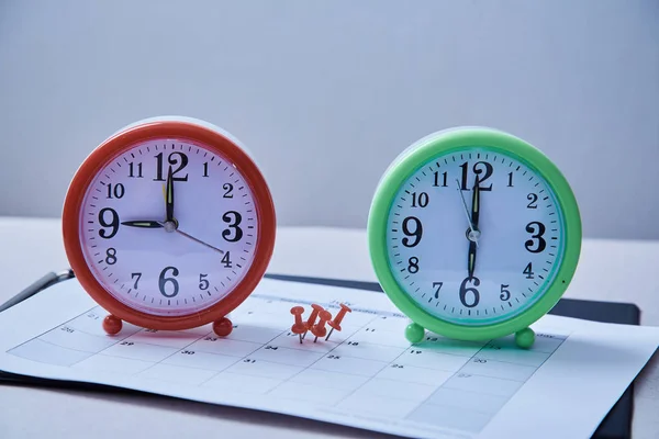 时间管理截止日期和计划概念: 两个桌面时钟之间的红色图钉. — 图库照片