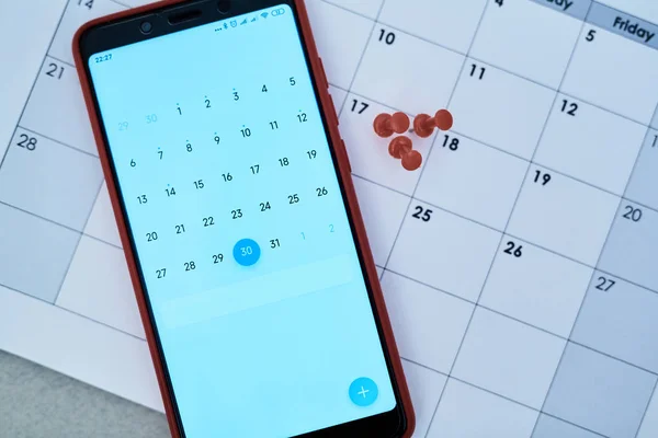 Time management deadline and schedule concept: calendar on the smartphone screen and pushpin