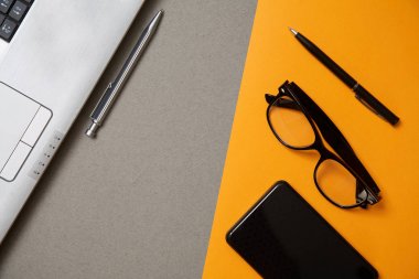 Bloglama, blog ve blogger veya sosyal medya kavramı: bir dizüstü bilgisayar, gözlük ve gri ve sarı arka plan üzerinde harici bir sabit disk. Düz yatıyordu