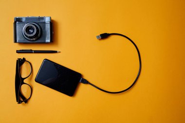 Bloglama, blog ve blogger veya sosyal medya kavramı: gözlük, fotoğraf makinesi ve sarı bir arka plan üzerinde harici bir sabit disk. Düz yatıyordu