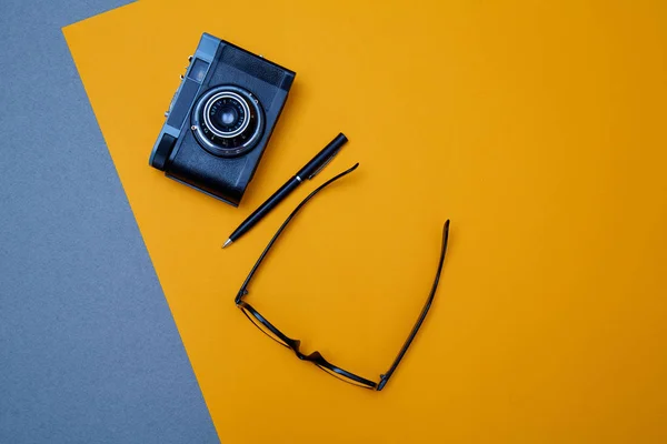 Bloglama, blog ve blogger veya sosyal medya kavramı: gözlük, fotoğraf makinesi ve sarı arka plan üzerinde bir kalem. Düz yatıyordu — Stok fotoğraf