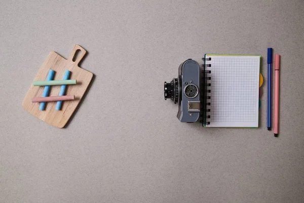 Food blogging, blog and blogger or social media concept: symbol hashtag, notepad and a retro photo camera on a grey background. Flat lay