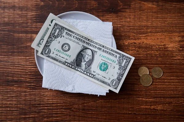 Restoran ipuçları veya bahşiş. Bir tabakta banknotlar ve madeni paralar