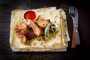 Restoran menüsü için ızgara yemekleri. Ahşap arka plan. Kızarmış veya ızgara kuzu kaburga, soğan ve sos.