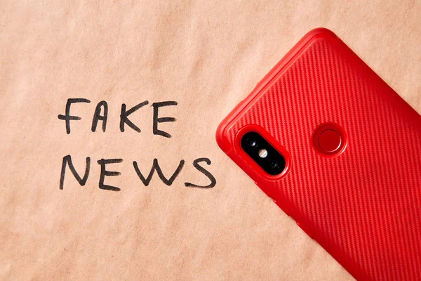Fake news, disinformation or false information and propaganda concept. Phone in the background with the inscription