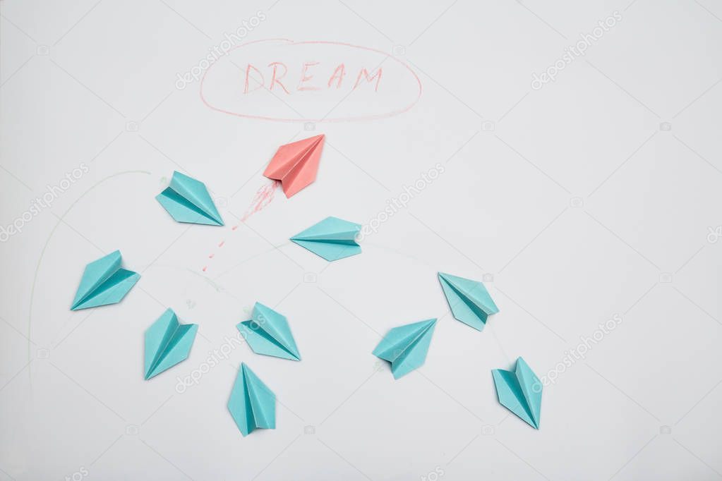 Business motivation, achieving goal and dream: The red plane of the paper escaping from the group