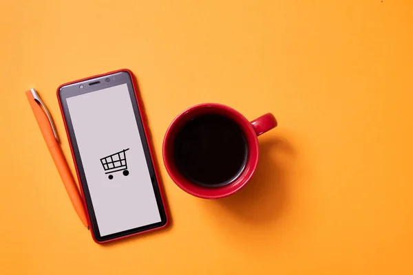 Online winkelen en e-commerce. Smartphone en een kopje koffie op een gele achtergrond — Stockfoto