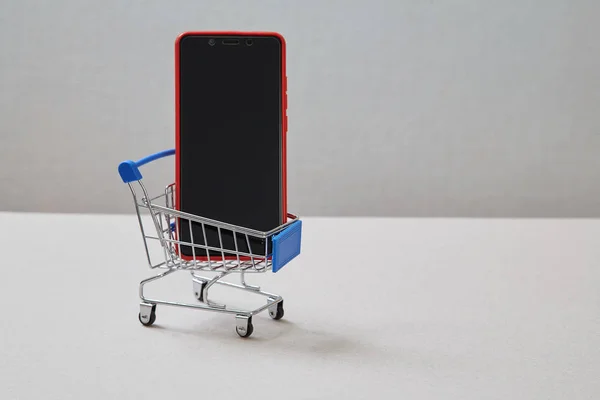 Web Store en onlineshopping concept. Smartphone en winkelmandje — Stockfoto