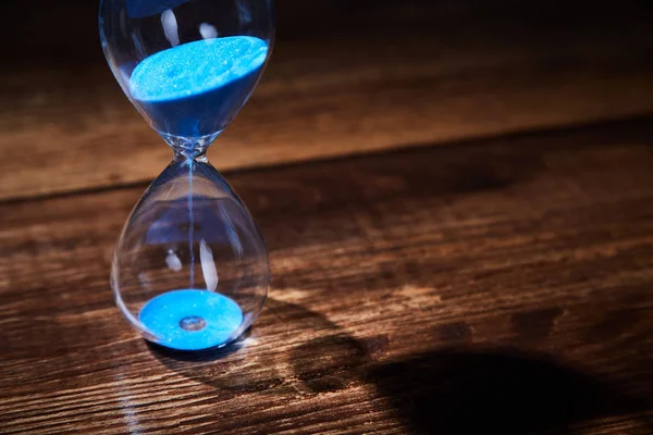 Zaman geçti, son tarih, aciliyet kavramı. Zaman yönetimi. Ahşap arka planda mavi kum saati. Kopyalama alanı