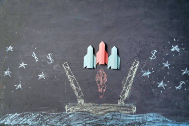 Ekip çalışması, finans, yatırım, tasarruf ve başlangıç konsepti. Kağıt roketlerden oluşan bir ekip boyalı fırlatma rampasından havalandı.