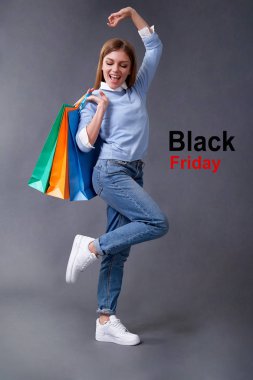 Satış, alışveriş, indirim ve Black Friday konsepti. Gri bir arka plan üzerinde duran renkli çanta ile Duygusal kız.