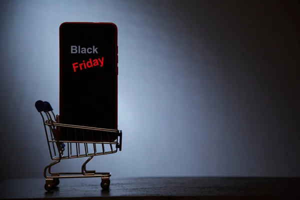 Black Friday, online alışveriş ve satış konsepti. Süpermarket ve indirim. Alışveriş sepetinde akıllı telefon