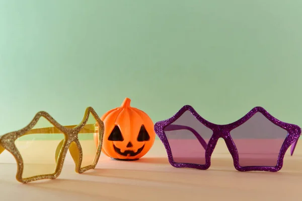 할로윈 컨셉이야. 가을 연휴에는 장식용 장식을 하고 있다. 안경의 장식. 플라스틱 호박. 복사 공간. 녹색 배경 — 스톡 사진