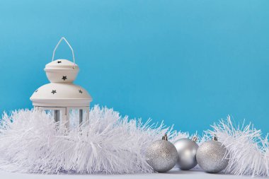 Beyaz fener gümüş parıltılı toplar ve tüylü süsler. Noel ve mutlu yıllar konsepti. Uzayı kopyala Mavi arkaplan