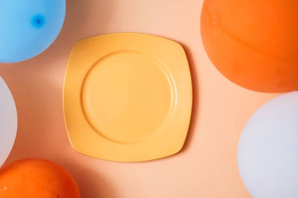Праздничный фон. День рождения. Детский праздник. Вид сверху на тарелку и воздушные шары на персиковом заднике — стоковое фото