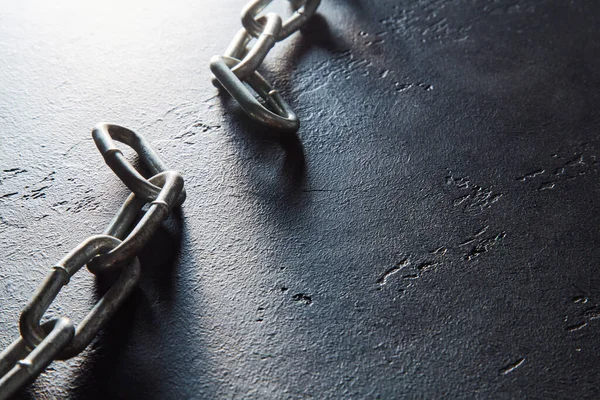 Koyu dokulu arka planda parçalanmış zincir, yazı için yer. Kırık metal zincir, kopyalama uzayı. Özgürlük, özgürlük kavramı