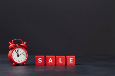 Toptan satış. Kırmızı küpler, bir beyaz, siyah arka planda çalar saat, kopyalama alanı. Satış zamanı. Kara Cuma. Satıldı..