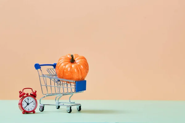 Hora del festival de la cosecha. Feliz día de Acción de Gracias. Carro de compras con miniatura de calabaza y despertador rojo. Copiar espacio —  Fotos de Stock