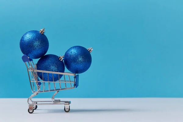 Bolas decorativas en carrito aislado sobre fondo azul. Copiar espacio. Feliz año nuevo y el concepto de Navidad —  Fotos de Stock