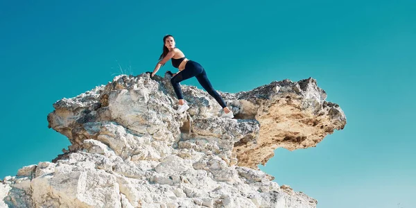 Aktív életmód. Egy nő mászik fel a hegyre. Sziklamászás. Erős és erős sportoló. Természetedzés. Kék ég. — Stock Fotó