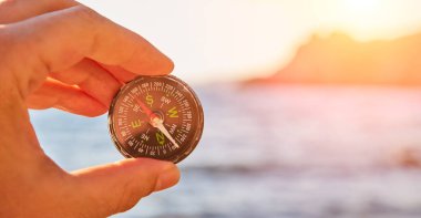 Seyahat tutkusu. Dünyayı dolaşmak. Seyahat zamanı. El ele tutuşan pusula. Yürüyüş. Deniz, arka planda dağ