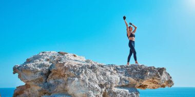 Deniz Burnu. Bakire doğa. Tren için rahat spor giyim. Spor ve Sağlık. Yoga ve pilates. Keskin kayalıklarda poz veren sağlıklı kadın