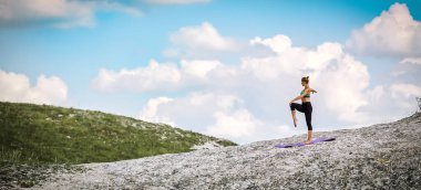 Kadın açık havada esneklik eğitimi alıyor. Yoga ve tefekkür. Sportif yaşam tarzı. Bacak üzerinde dengede duran bir kadın. Boşluğu kopyala