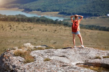 Uçurumun kenarında duran kadın nefes kesici manzaranın tadını çıkarıyor. Tatil zamanı. Dünya seyahati. Dağlara macera gezisi.
