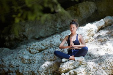 Rahat spor giyimli bir bayan. Meditasyon ve Yoga zamanı. Pilates. Kadın temiz hava üzerine meditasyon yapıyor. Keskin tepe. Boşluğu kopyala.