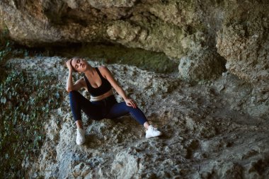 Yorucu egzersizden sonra dinlenen bir kadın. Açık hava sporu. Sabah koşusu. Sağlıklı aktif konsept. Arkaplanda dağ