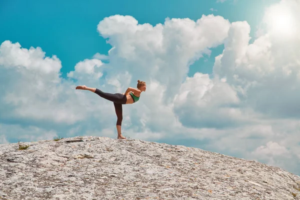 A hölgy egyensúlyozó pózban áll. Jógaidő és Pilates ötlet. Kék felhős ég. Szűz természet vagy edzés a friss levegőn — Stock Fotó