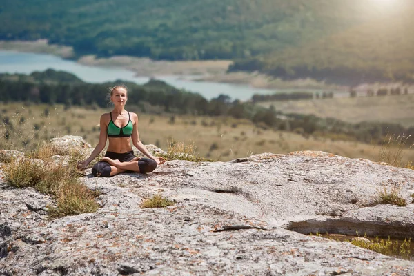 Lotus pozisyonunda bir kadın. Kadın, temiz hava üzerine meditasyon yapıyor. Spor, spor ya da sağlıklı yaşam tarzı konsepti. Yeşil çayırlar.