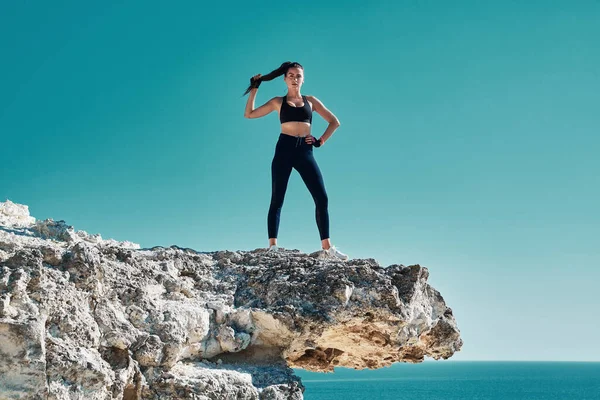 Mujer en forma posando en un acantilado afilado. Paisaje marino de naturaleza virgen. Deporte, Salud o Yoga y Pilates idea. — Foto de Stock