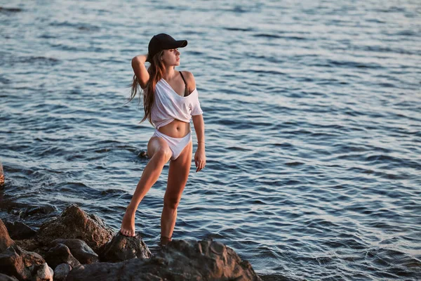 Vrouw poserend op de kustlijn met pet op. Relax en overpeinzing idee. Rustige zee en natuur landschap. Zomervakantie — Stockfoto