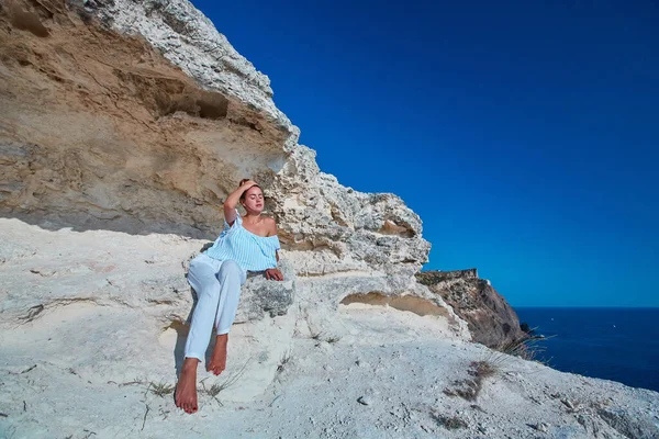 Time to rest. Dreaming and contemplation. Relaxing moment. Lovely woman sitting on rock. Breathtaking sea landscape