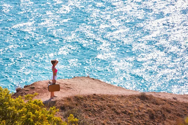 Passion pour le voyage. L'été et les vacances. Femme errant avec valise sur le sentier de montagne. Mer brillante, espace de copie — Photo